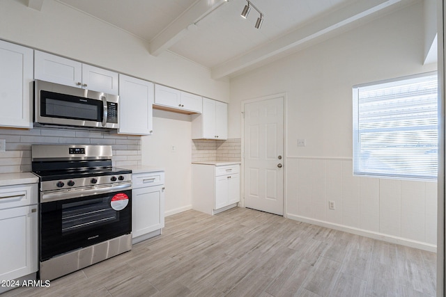 kitchen featuring white cabinets, lofted ceiling with beams, stainless steel appliances, light countertops, and light wood-type flooring