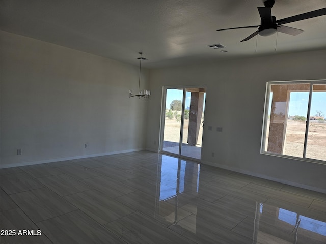 unfurnished room with visible vents, baseboards, ceiling fan with notable chandelier, and a healthy amount of sunlight