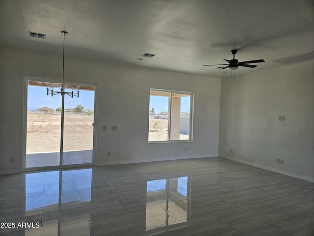 unfurnished room featuring baseboards, ceiling fan with notable chandelier, and visible vents