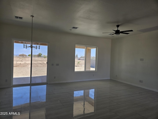 spare room with visible vents, baseboards, and ceiling fan with notable chandelier