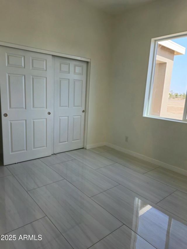 unfurnished bedroom with baseboards and a closet