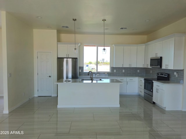 kitchen featuring visible vents, a center island with sink, a sink, appliances with stainless steel finishes, and backsplash