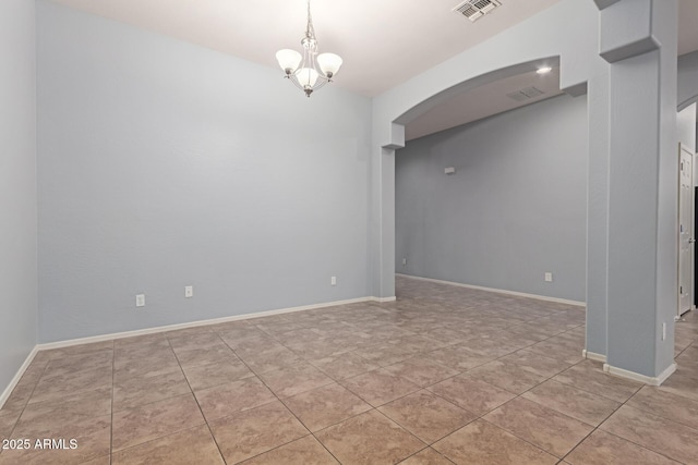 tiled spare room with an inviting chandelier