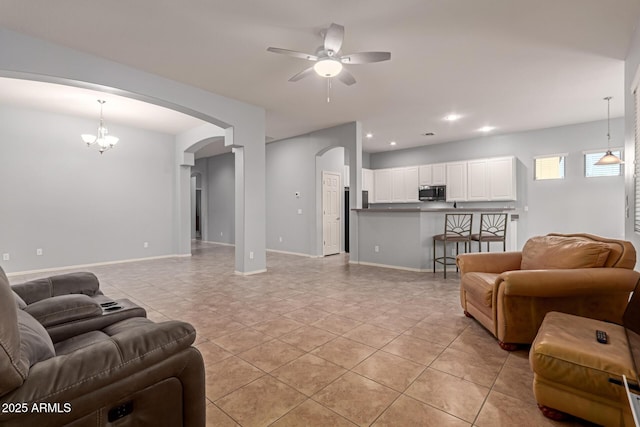 living room with ceiling fan with notable chandelier and light tile patterned flooring