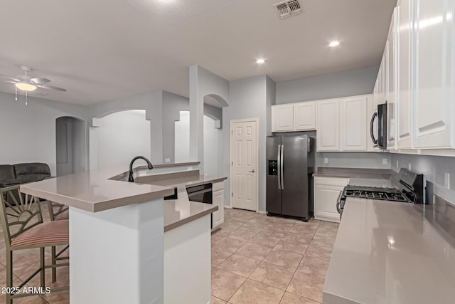 kitchen featuring white cabinets, appliances with stainless steel finishes, a breakfast bar area, and light tile patterned flooring