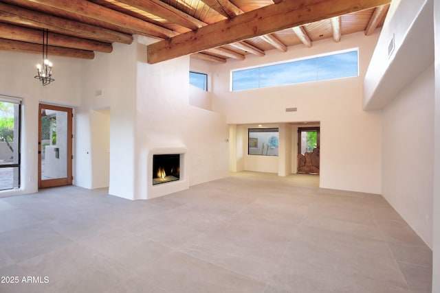 1637 N Quartz Valley Rd, Scottsdale, AZ 85266 - unfurnished living room with a high ceiling, a wooden ceiling with exposed beams, a large fireplace, a chandelier, and light tile patterned flooring