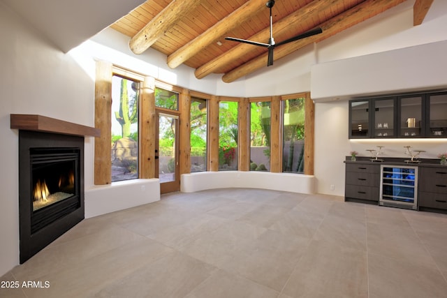 1637 N Quartz Valley Rd, Scottsdale, AZ 85266 - unfurnished living room with beverage cooler, a wooden ceiling with exposed beams, bar area, a lit fireplace, and light tile patterned floors