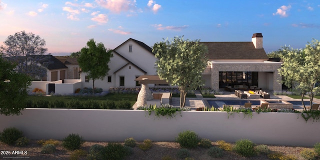 view of front of house featuring stone siding, a fenced front yard, a chimney, and stucco siding