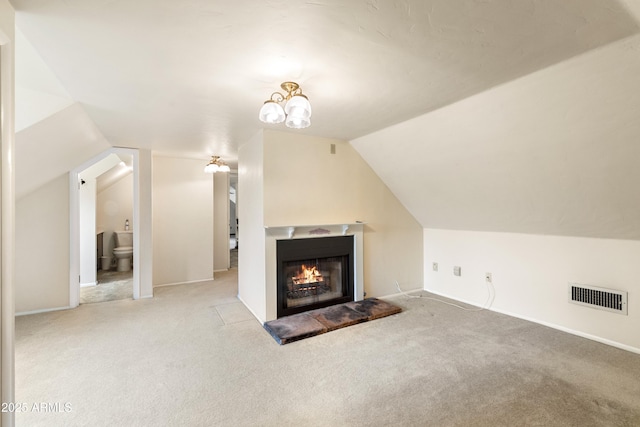 additional living space featuring carpet flooring, a warm lit fireplace, vaulted ceiling, and visible vents