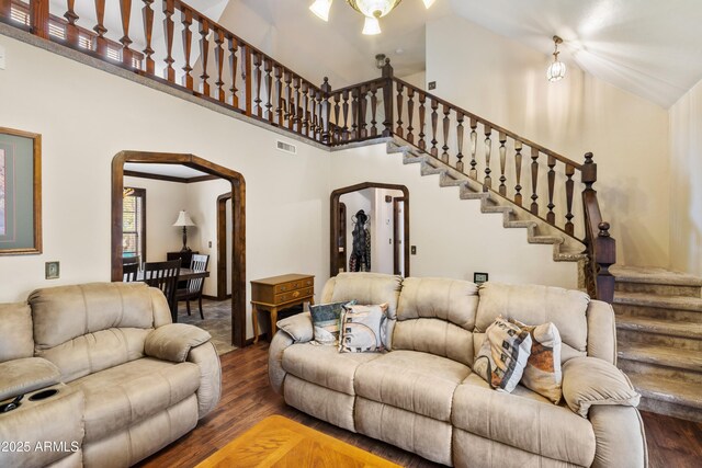 living room with arched walkways, stairs, visible vents, and wood finished floors