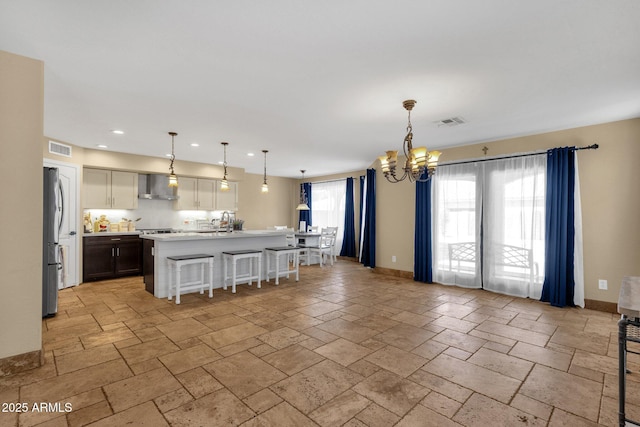 508 W San Angelo St, Gilbert, AZ 85233 - kitchen featuring freestanding refrigerator, wall chimney exhaust hood, a chandelier, stone tile flooring, and recessed lighting
