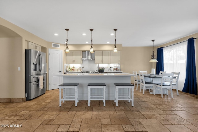 508 W San Angelo St, Gilbert, AZ 85233 - kitchen featuring stainless steel fridge with ice dispenser, stone tile floors, wall chimney range hood, recessed lighting, and light countertops