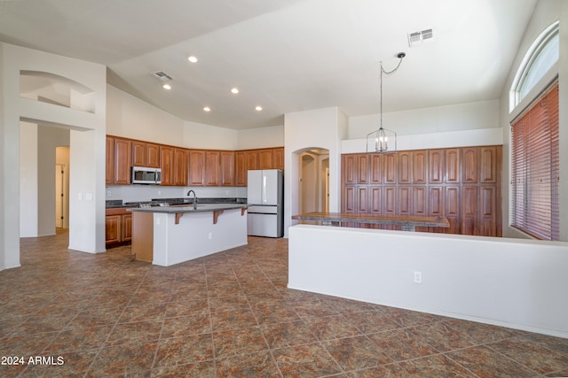 kitchen with a breakfast bar, dark countertops, stainless steel microwave, visible vents, and freestanding refrigerator