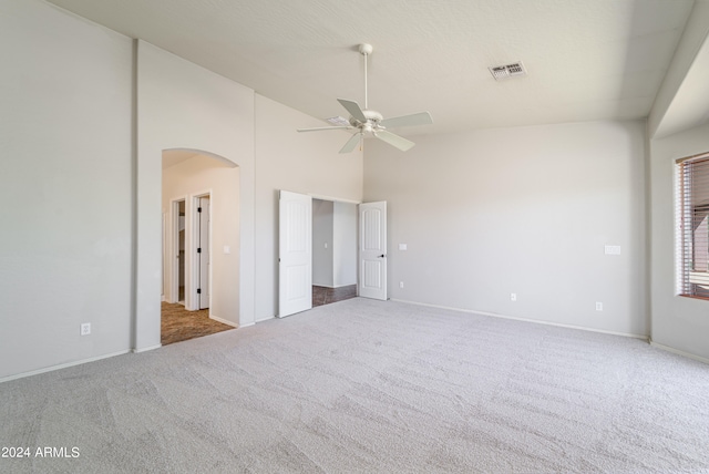 unfurnished bedroom featuring high vaulted ceiling, visible vents, arched walkways, and carpet flooring