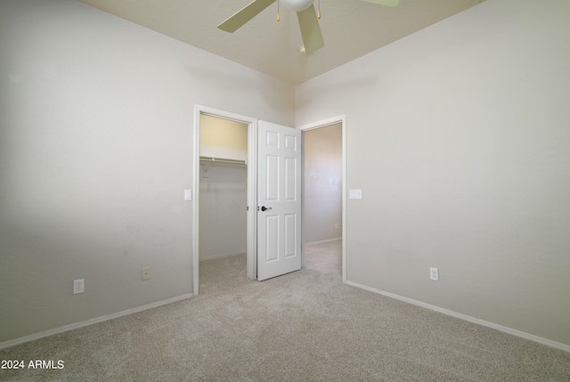 unfurnished bedroom with baseboards, a ceiling fan, carpet, a walk in closet, and a closet