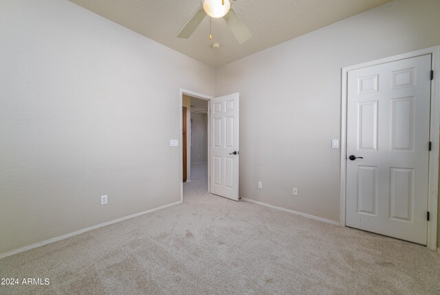 carpeted empty room featuring a ceiling fan and baseboards