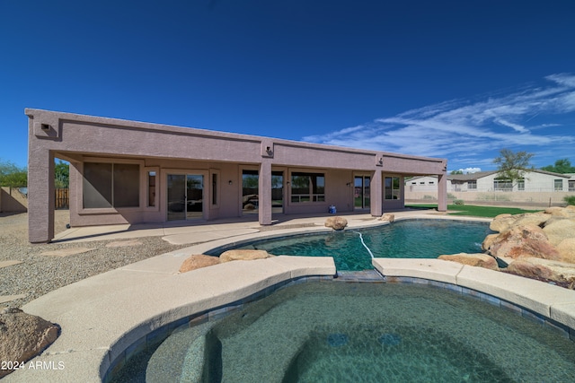 pool with an in ground hot tub, a patio area, and fence