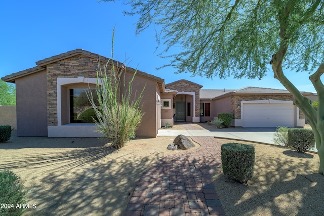 view of front of house with stone siding, an attached garage, driveway, and stucco siding