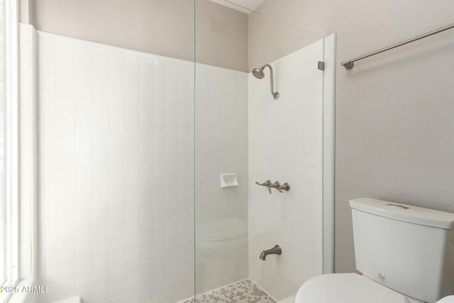 bathroom with a tile shower and toilet