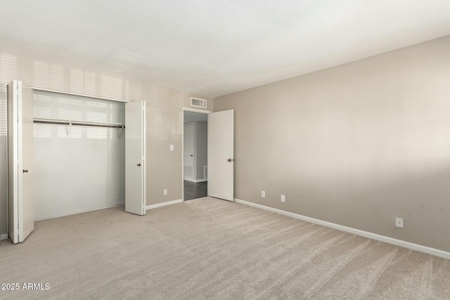 unfurnished bedroom with light colored carpet and a closet