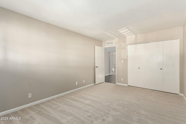 unfurnished bedroom with light colored carpet and a closet