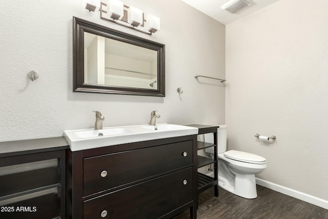 bathroom with wood-type flooring, vanity, and toilet