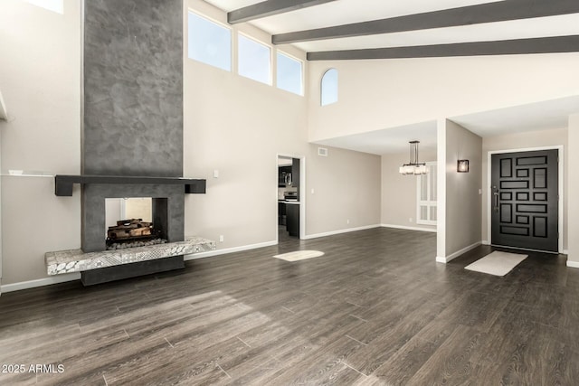 unfurnished living room featuring beamed ceiling, a multi sided fireplace, dark hardwood / wood-style floors, and a chandelier