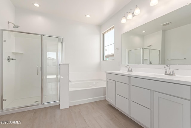 bathroom featuring a garden tub, a sink, a shower stall, and double vanity