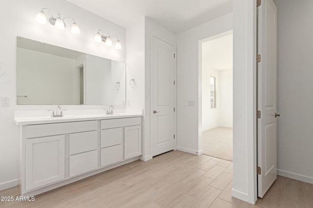 bathroom featuring double vanity, a sink, baseboards, and wood finished floors