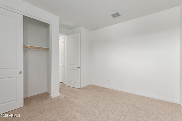 unfurnished bedroom featuring light carpet, a closet, visible vents, and baseboards