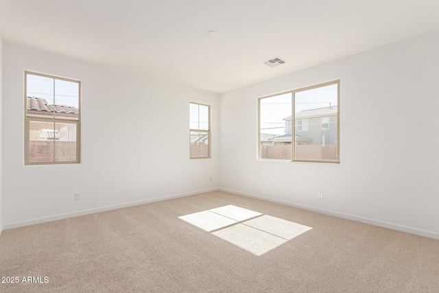 empty room featuring light colored carpet, visible vents, and baseboards