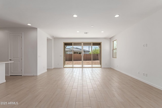 empty room featuring light wood-type flooring, visible vents, baseboards, and recessed lighting