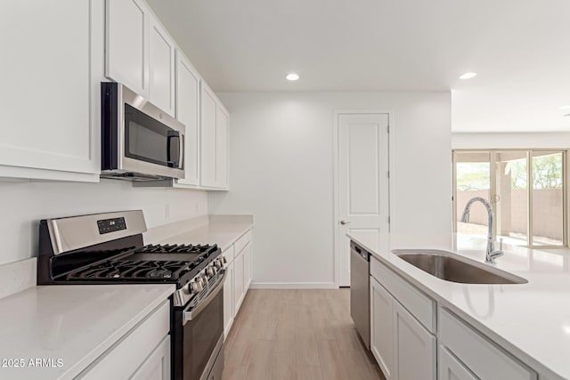 kitchen featuring white cabinets, appliances with stainless steel finishes, light countertops, and a sink