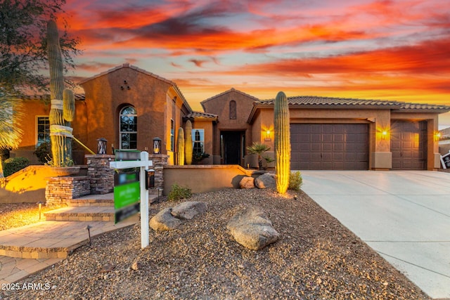 mediterranean / spanish home featuring a tile roof, driveway, an attached garage, and stucco siding