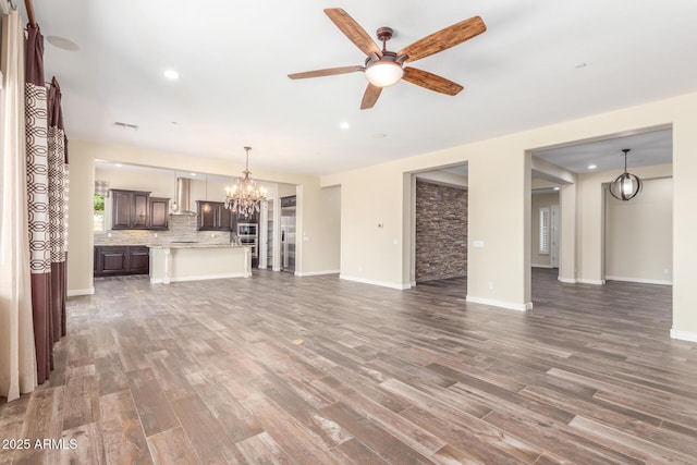 unfurnished living room with baseboards, visible vents, wood finished floors, and ceiling fan with notable chandelier