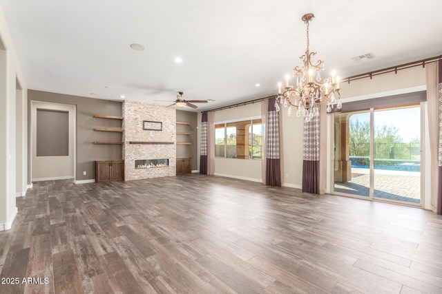 unfurnished living room with baseboards, visible vents, wood finished floors, and a stone fireplace