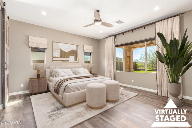 bedroom with wood finished floors, visible vents, and baseboards