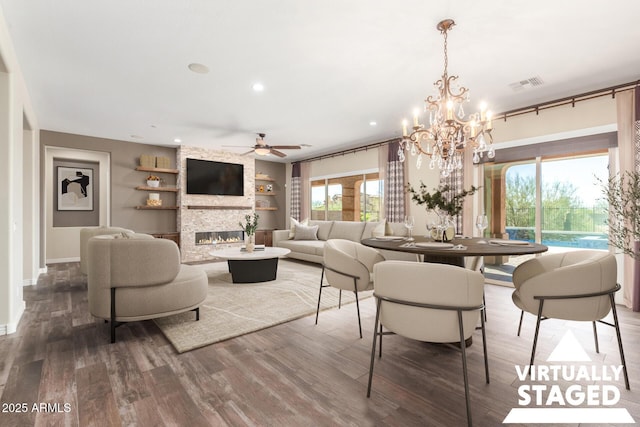 dining room with built in features, visible vents, a stone fireplace, and wood finished floors