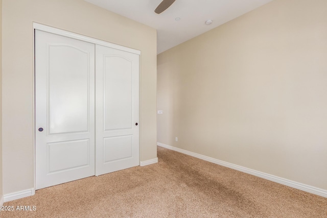 unfurnished bedroom with baseboards, a closet, a ceiling fan, and light colored carpet