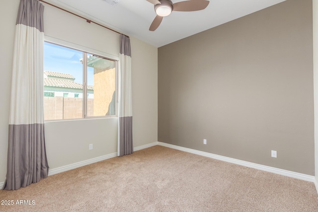 carpeted spare room featuring ceiling fan and baseboards