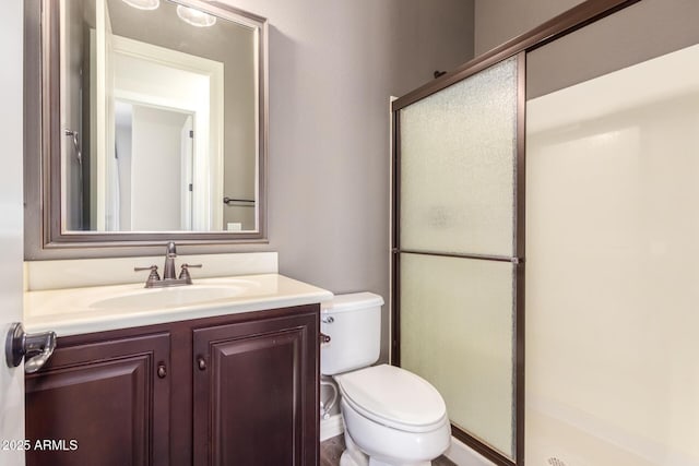 bathroom with a stall shower, vanity, and toilet