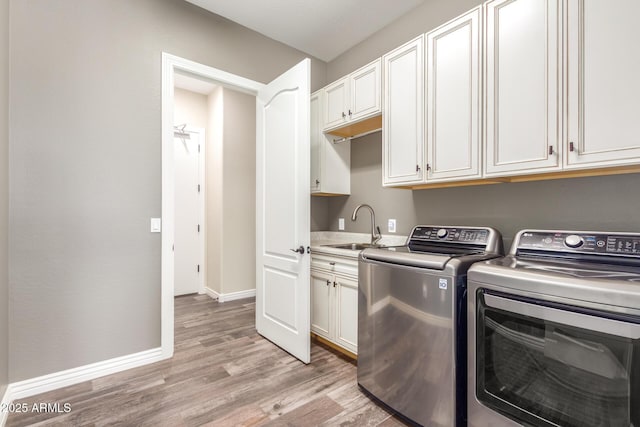 washroom featuring a sink, baseboards, light wood-type flooring, independent washer and dryer, and cabinet space