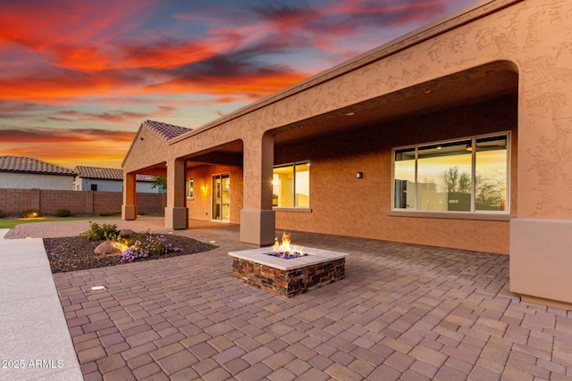 patio terrace at dusk with an outdoor fire pit and fence