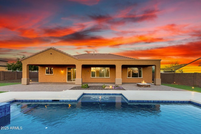 back of house with an outdoor fire pit, a fenced backyard, a patio, and stucco siding