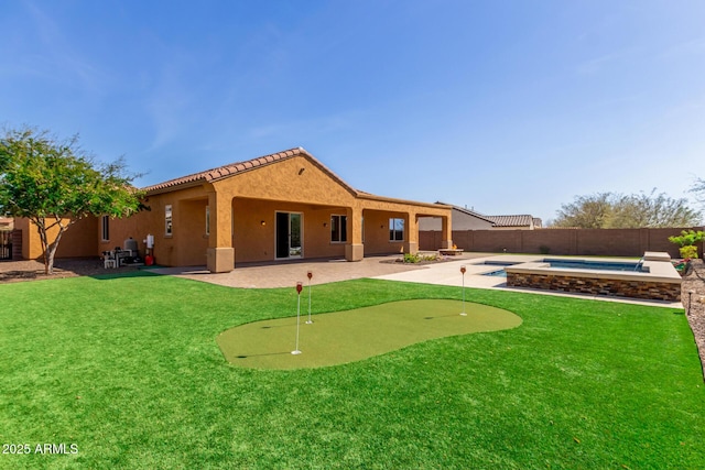 back of property featuring a lawn, a fenced in pool, a fenced backyard, a patio area, and stucco siding