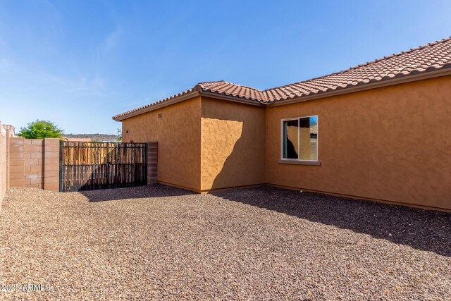 view of side of property with a tile roof, fence, a patio, and stucco siding