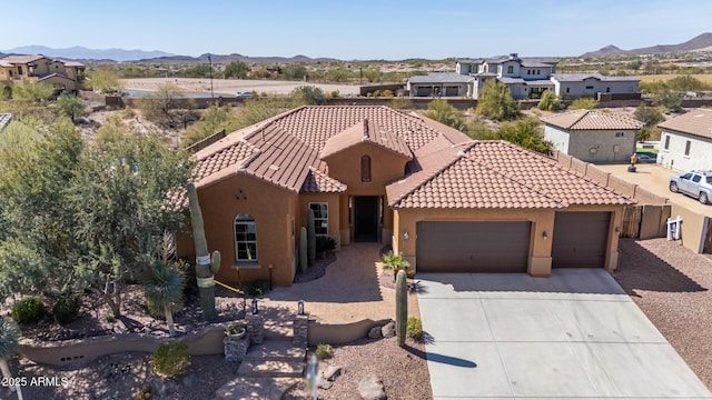 mediterranean / spanish-style house featuring concrete driveway, a mountain view, an attached garage, and stucco siding