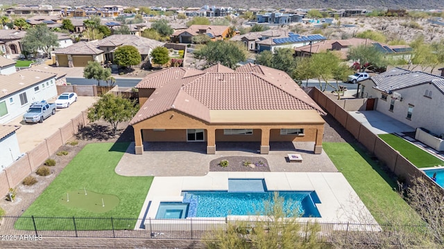 view of swimming pool featuring a residential view, a pool with connected hot tub, a fenced backyard, and a patio