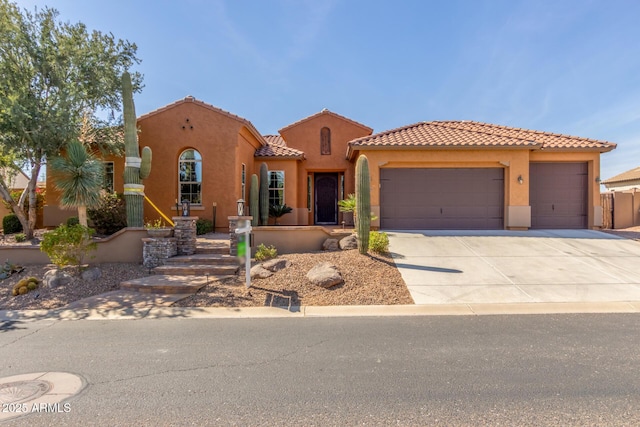 mediterranean / spanish-style house with a garage, a tiled roof, concrete driveway, and stucco siding