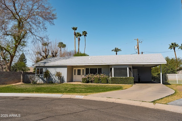 ranch-style home featuring concrete driveway, a front lawn, fence, and an attached carport